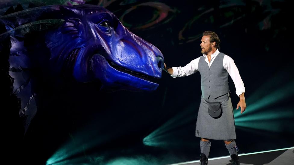 Kilted Sam Heughan with a giant model of the Loch Ness Monster