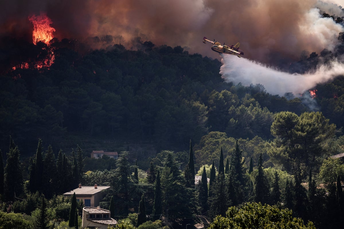 A French Civil Security Canadair CL-415 aircraft sprays water on a forest surrounding Cotignac, southeastern France.