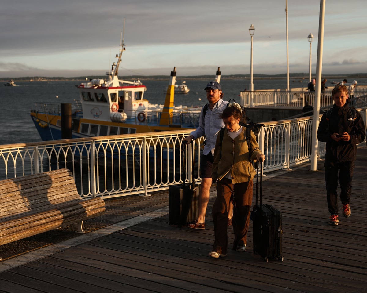 Holidaymakers from Lege-Cap-Ferret carry their belongings along the pier upon their arrival in Arcachon during an evacuation operation of the entire Cap-Ferret peninsula in southwestern France.