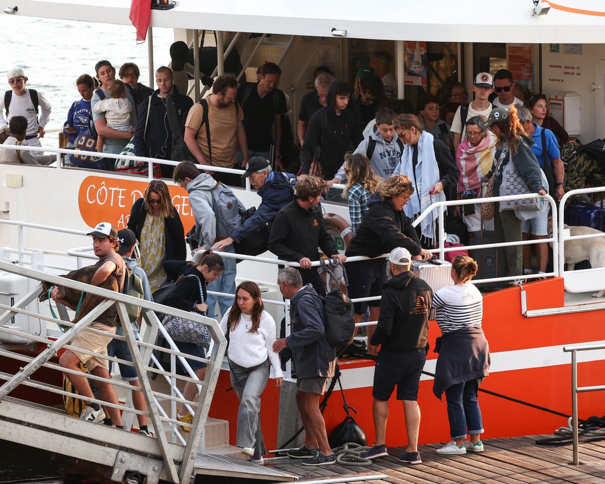 Holidaymakers from Lege-Cap-Ferret disembark from a boat upon their arrival in Arcachon during an evacuation operation of the entire Cap-Ferret peninsula, in southwestern France.
