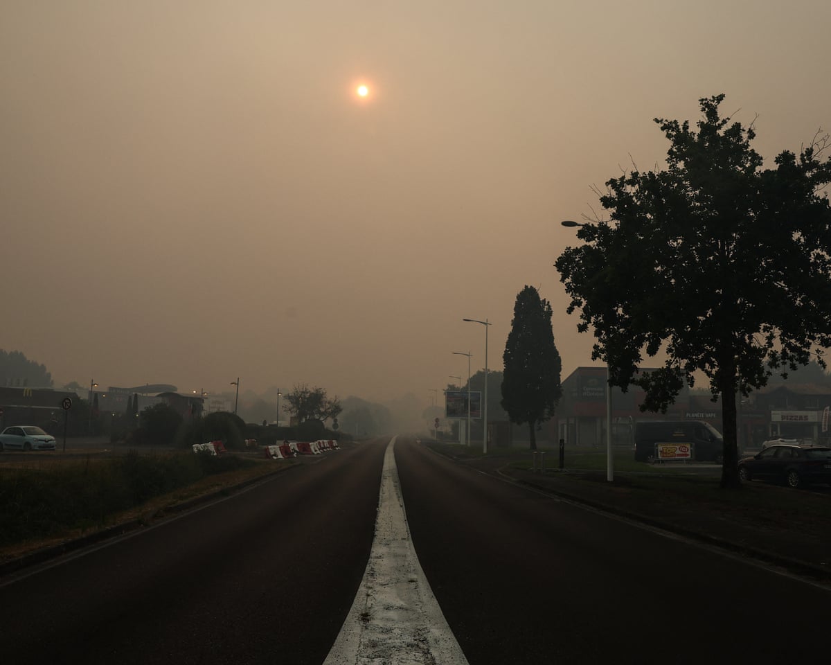The entrance of the town of Biscarosse, southwestern France, with a sky turned hazy yellowish-grey by the smoke of a wildfire spreading through the surrounding forest.