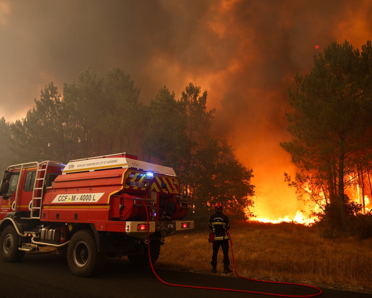 Firefighters try to extinguishing fires burning trees using a wildland water truck near Le Porge, southwestern France.