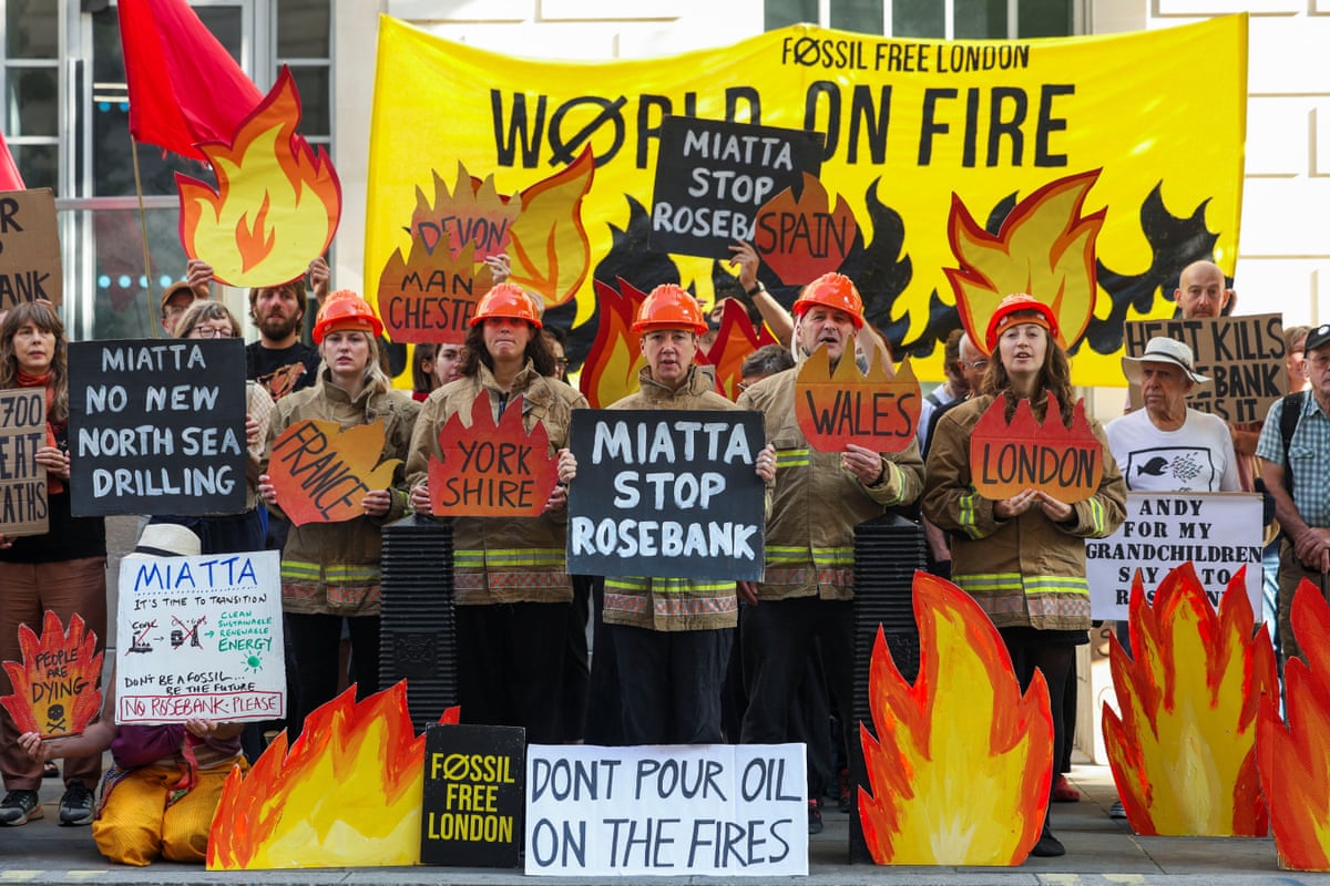 Demonstrators dressed as firefighters and flames holding signs saying 'Miatta stop Rosebank'