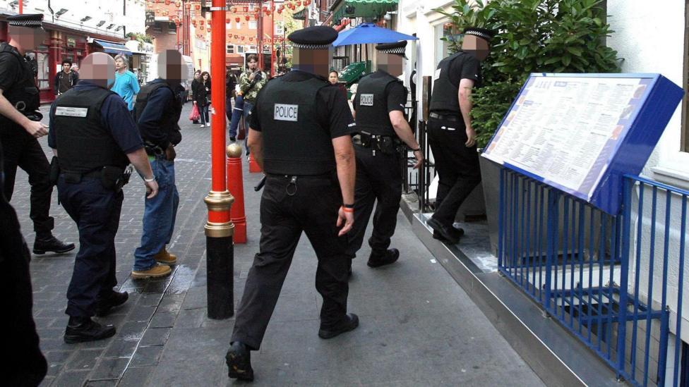 A group of uniformed police officers enter a restaurant in London's Chinatown.