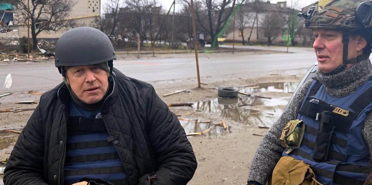 Boris Johnson in a military hard hat in Ukraine, with a uniformed soldier to his left
