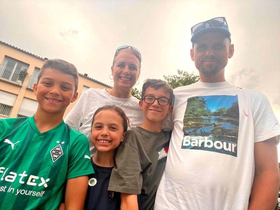 A family photo showing three children and their mother and father, all smiling.