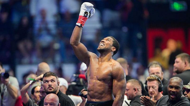 Anthony Joshua looks up, with a boxing glove raised, after his victory