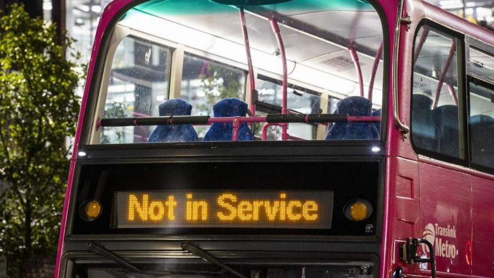 The top floor of a pink double decker bus sits empty. The illuminated sign at the front of the bus says 'not in service'.
