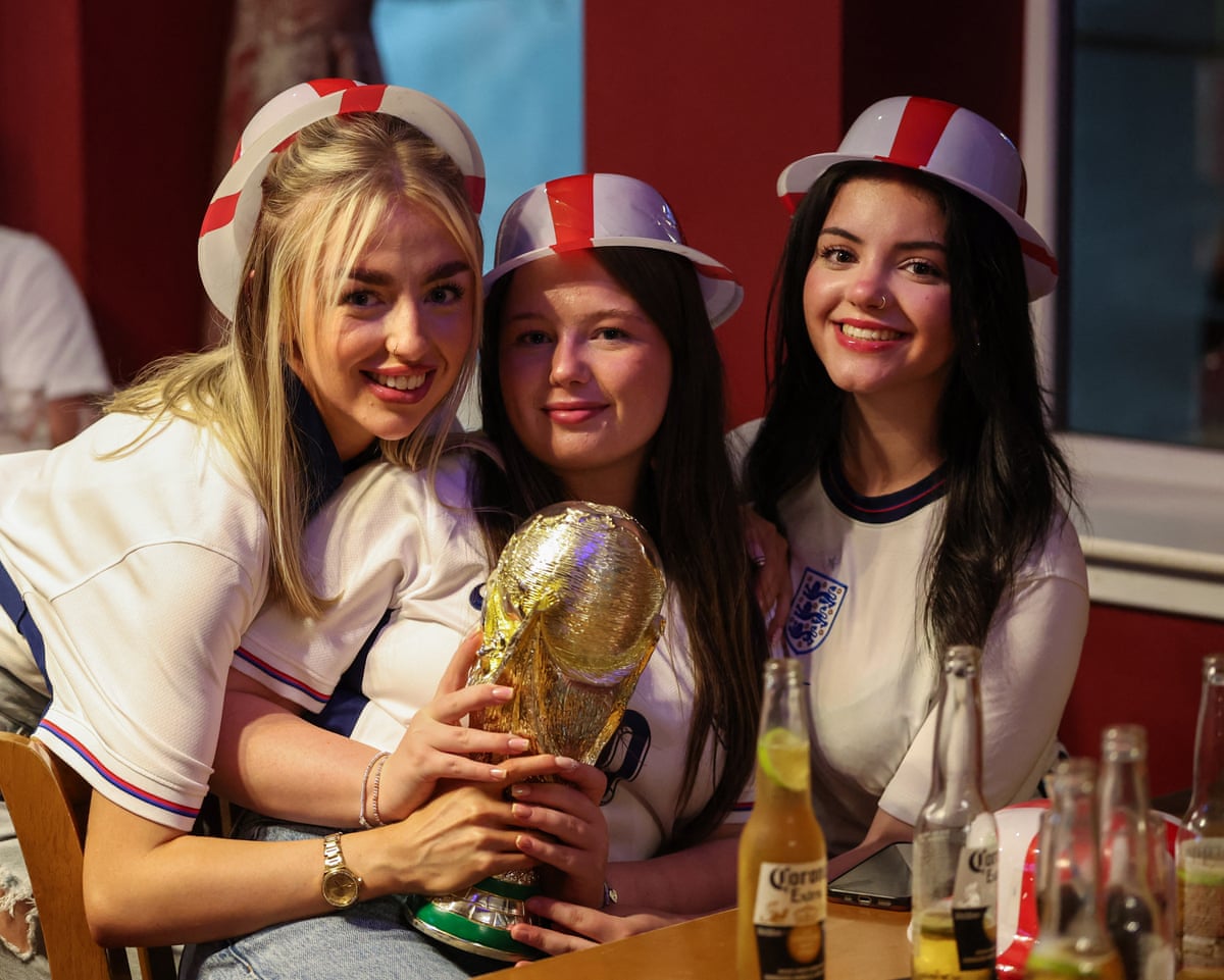 England supporters pose with a replica trophy as they wait for the start of the match between England and Mexico