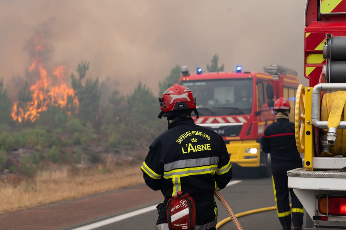 Firefighters work to control a wildfire burning alongside a road