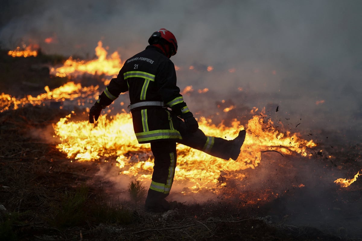 A firefighter works as flames burn during a wildfire