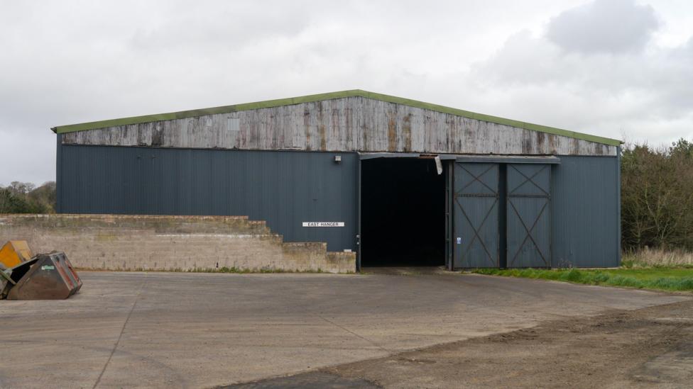 An old empty hangar building viewed across a paved area