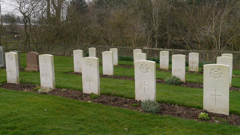 A series of white gravestones on grass
