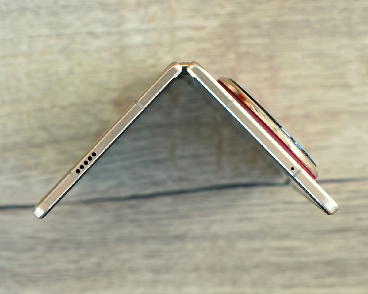 The Honor Magic V6 open at 90-degrees stood up on a wooden table.