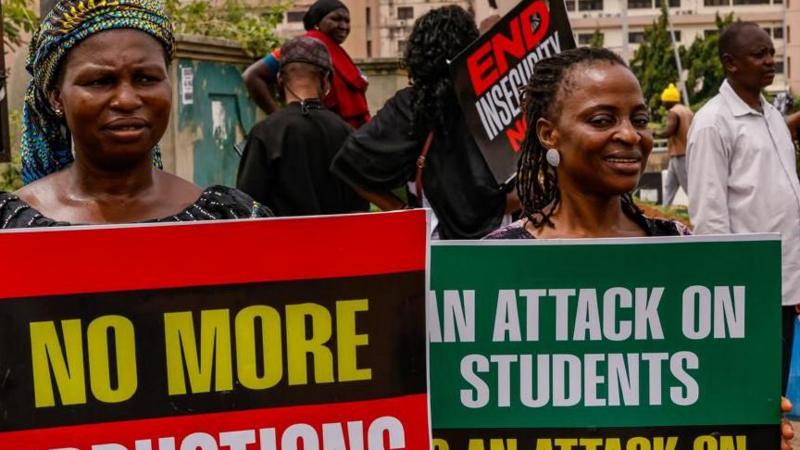 Two women protesters hold banners to protest recent school abductions in Nigeria