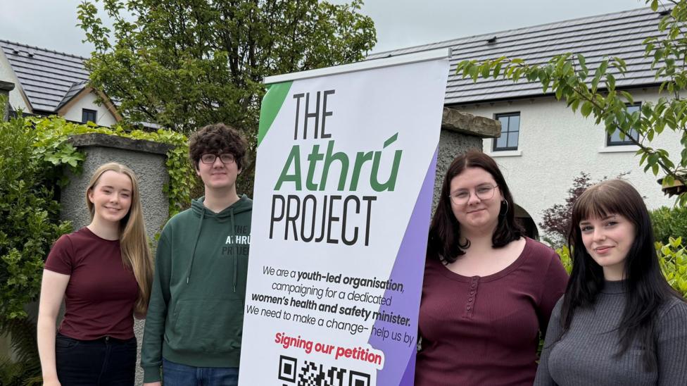 Four young people standing around a poster which says 'The Athrú Project'