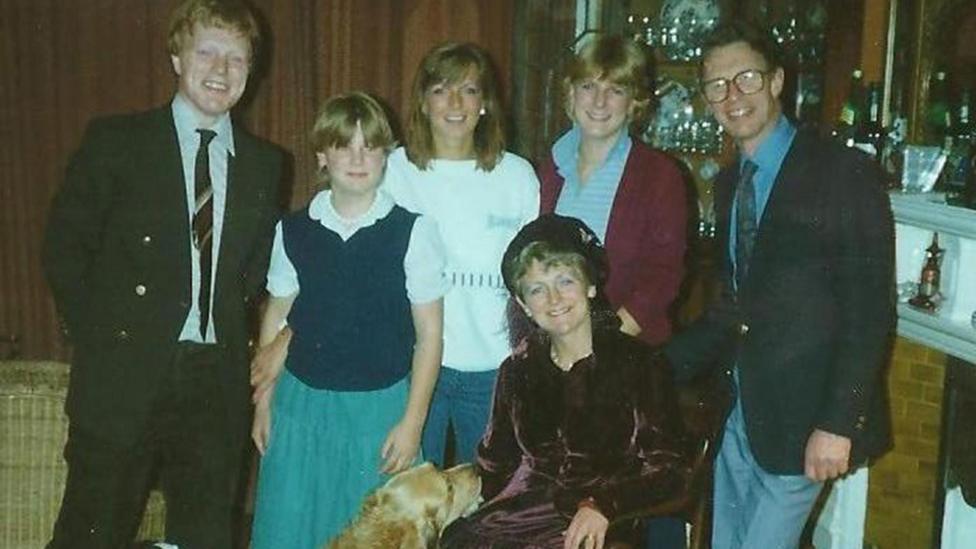 A grainy, aged, colour photo of Suzy, her brother, her two sisters and her parents. 