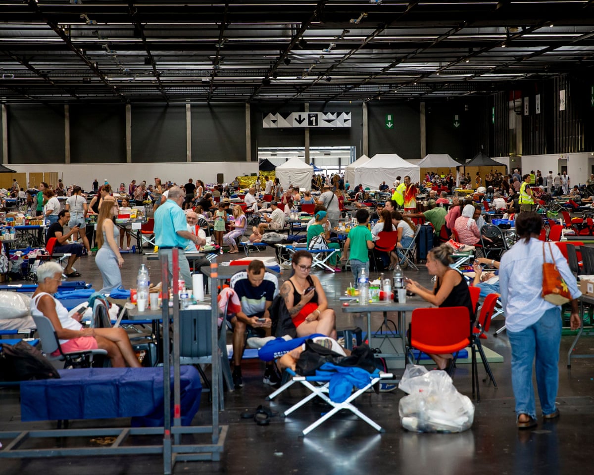 Thousands of people evacuated from their homes rest at the Bordeaux Exhibition Centre, which has been converted into a temporary emergency shelter following a major wildfire affecting the Gironde department in southwestern France.