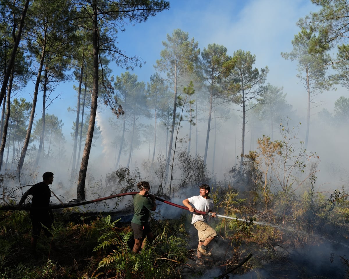 A group hold a firehose and try to suppress a fire near Lacanau, as wildfires rage outside Bordeaux, France.