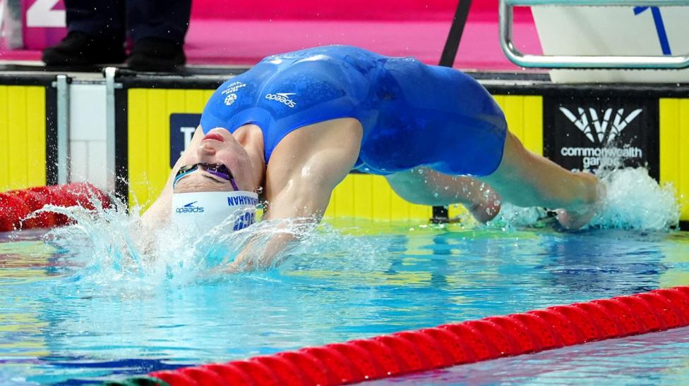 Katie Shanahan, wearing a blue swimming costume, dives into the pool during a race at the Commonwealth Games.