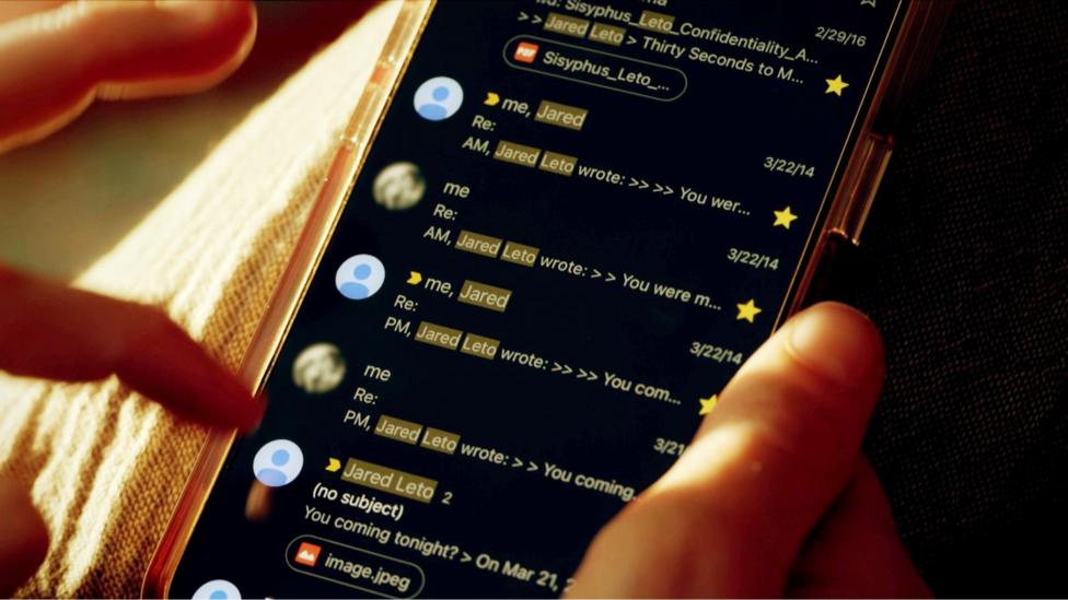 A still image of a woman scrolling through her phone, showing messages between 