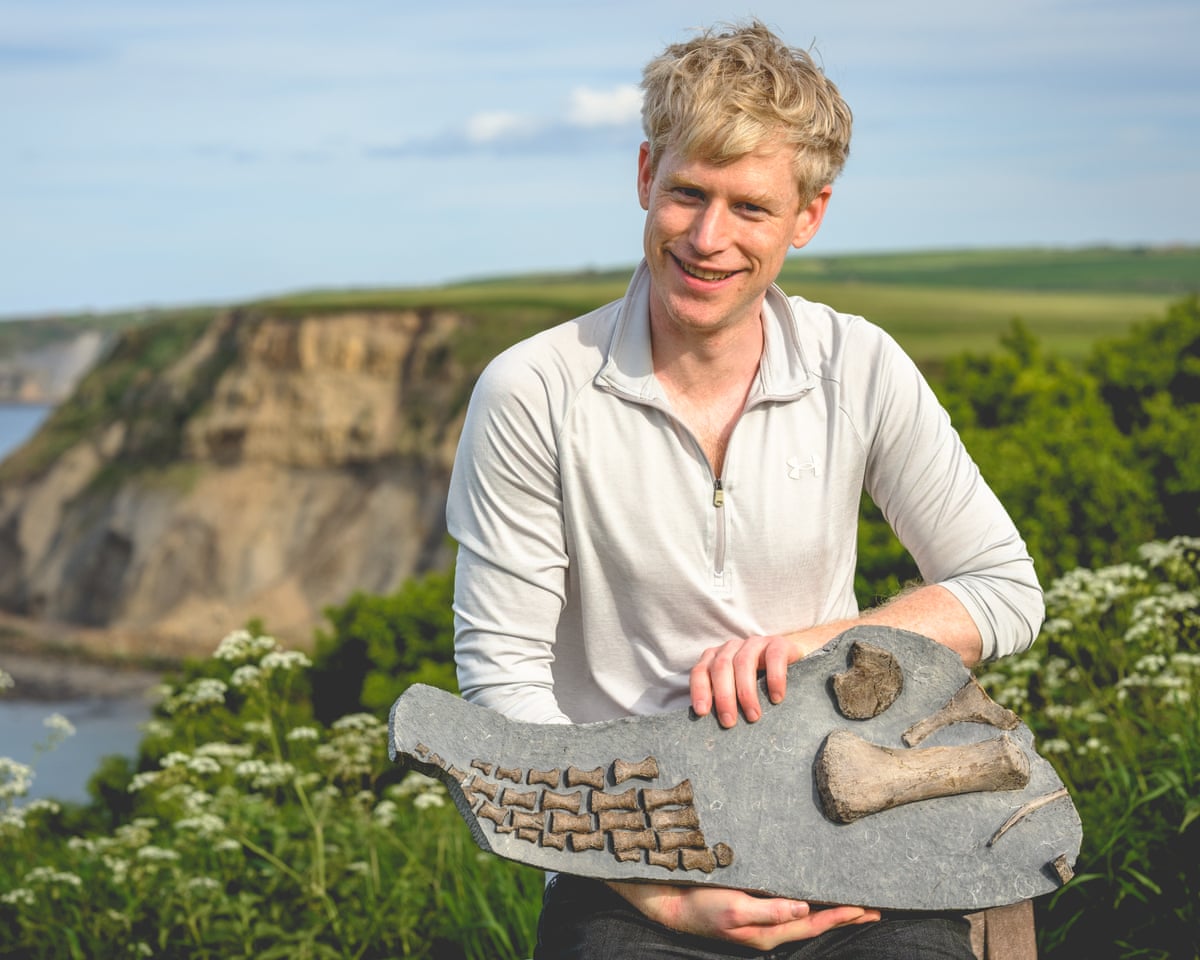 Matt Myerscough, a blond man holding a dinosaur fossil and smiling