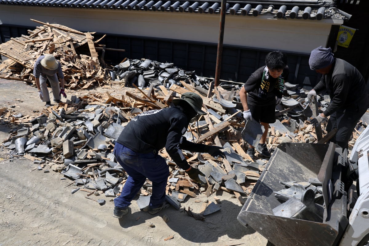 Four people clearing rubble on a street.