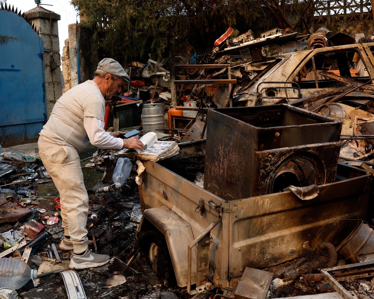 A man skims through a book as he surveys the extensive damage in his burned-out home, which sits on a plot where he stores scrap metal, following a devastating wildfire in Pelayos de la Presa, 65 kilometers west of Madrid, Spain.
