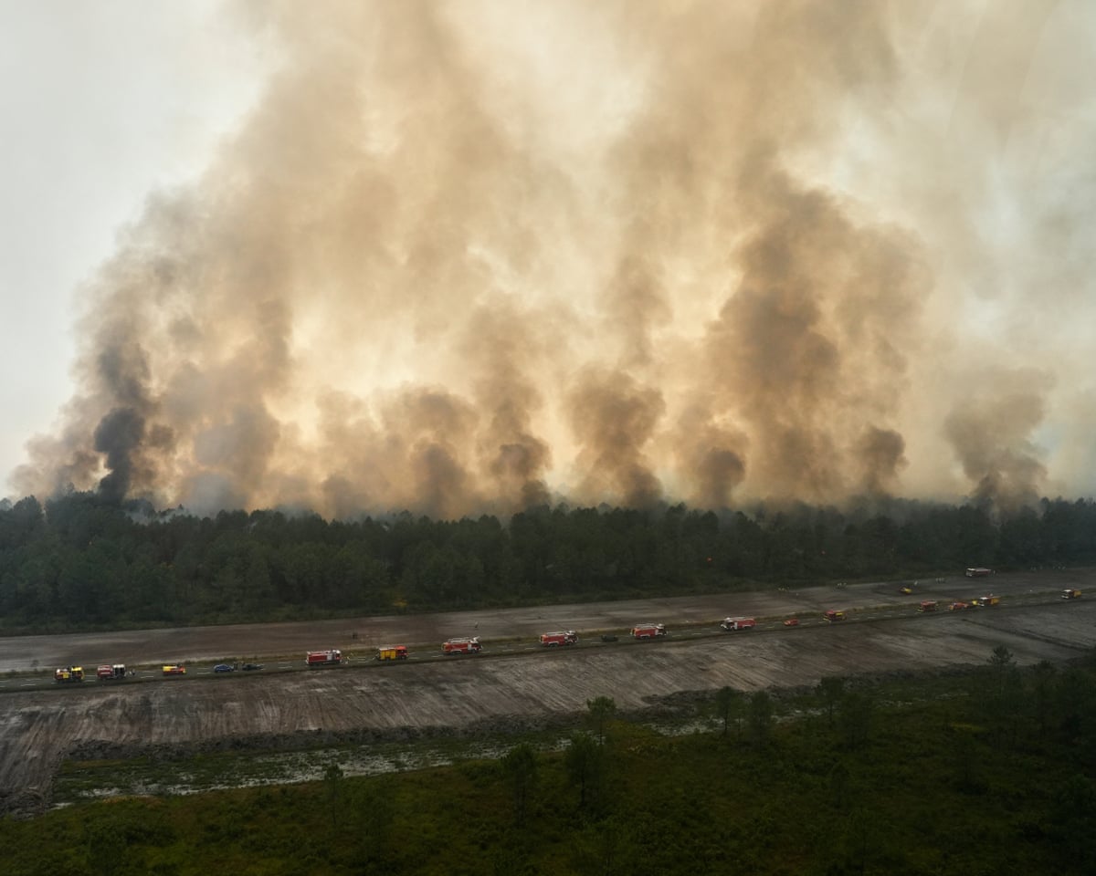 This aerial view taken from a Civil Security helicopter shows firefighting vehicles lined up along a road to suppress a wildfire near Ares, southwestern France.