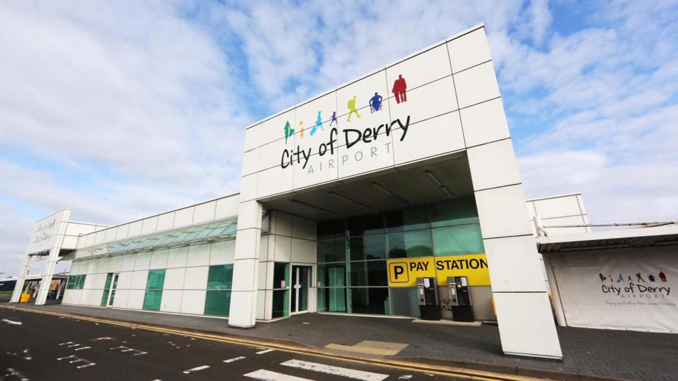 City Of Derry Airport entrance from the front. A large white building with a number of signs.