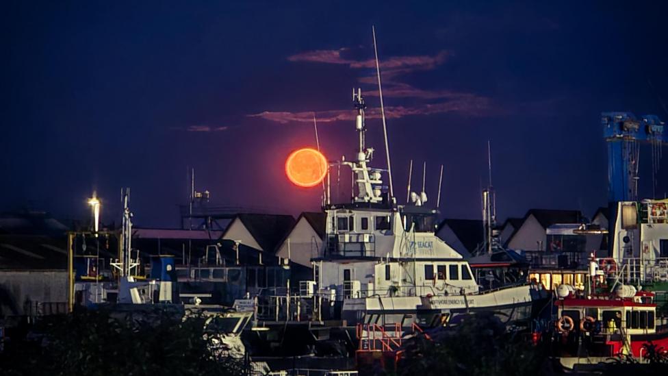 The Buck Moon spotted above a harbour full of boats in Great Yarmouth.