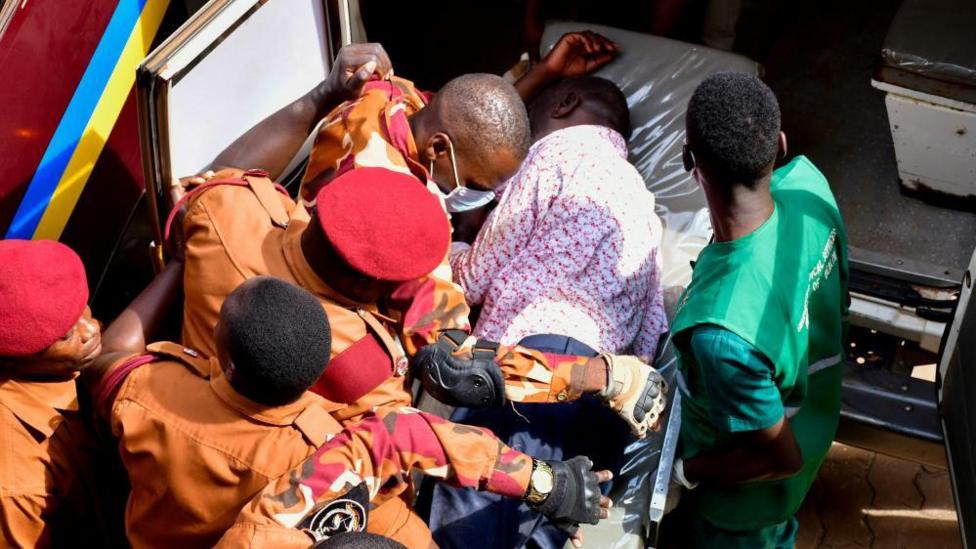 Kizza Besigye is put in an ambulance by uniformed prison guards