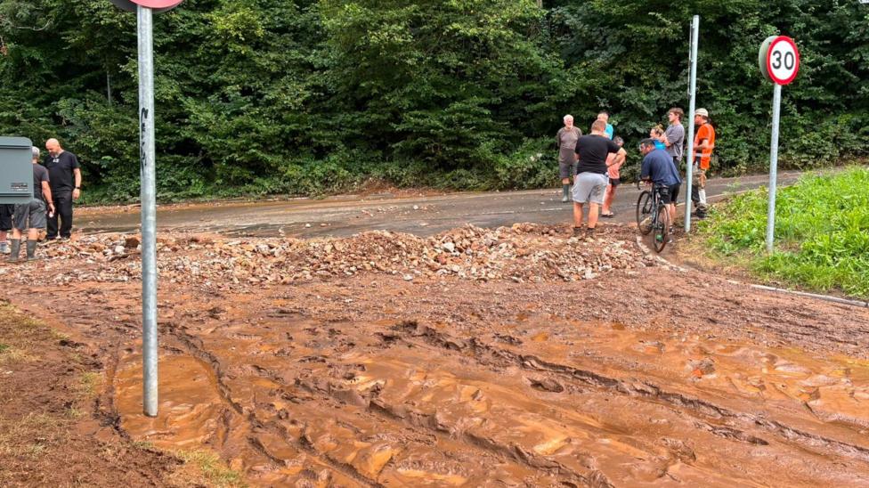 Flooding at Gwaelod-y-Garth, Taff's Well, Cardiff. Road full of mud and stones. Piles of wet mud left behind from the flooding.