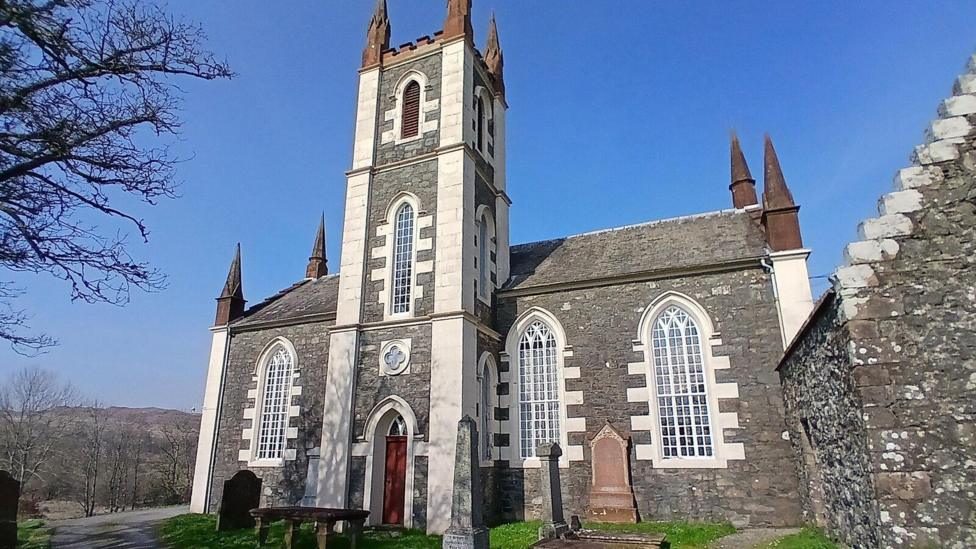 An impressive granite church with white features and some gravestones in front of it