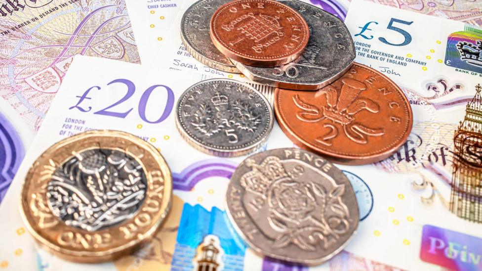 UK bank notes and coins are lying on a flat surface.