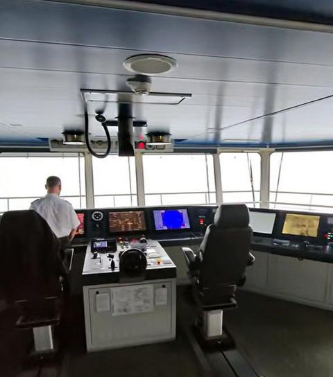 The bridge of a ferry including a member of staff who is being filmed from behind.