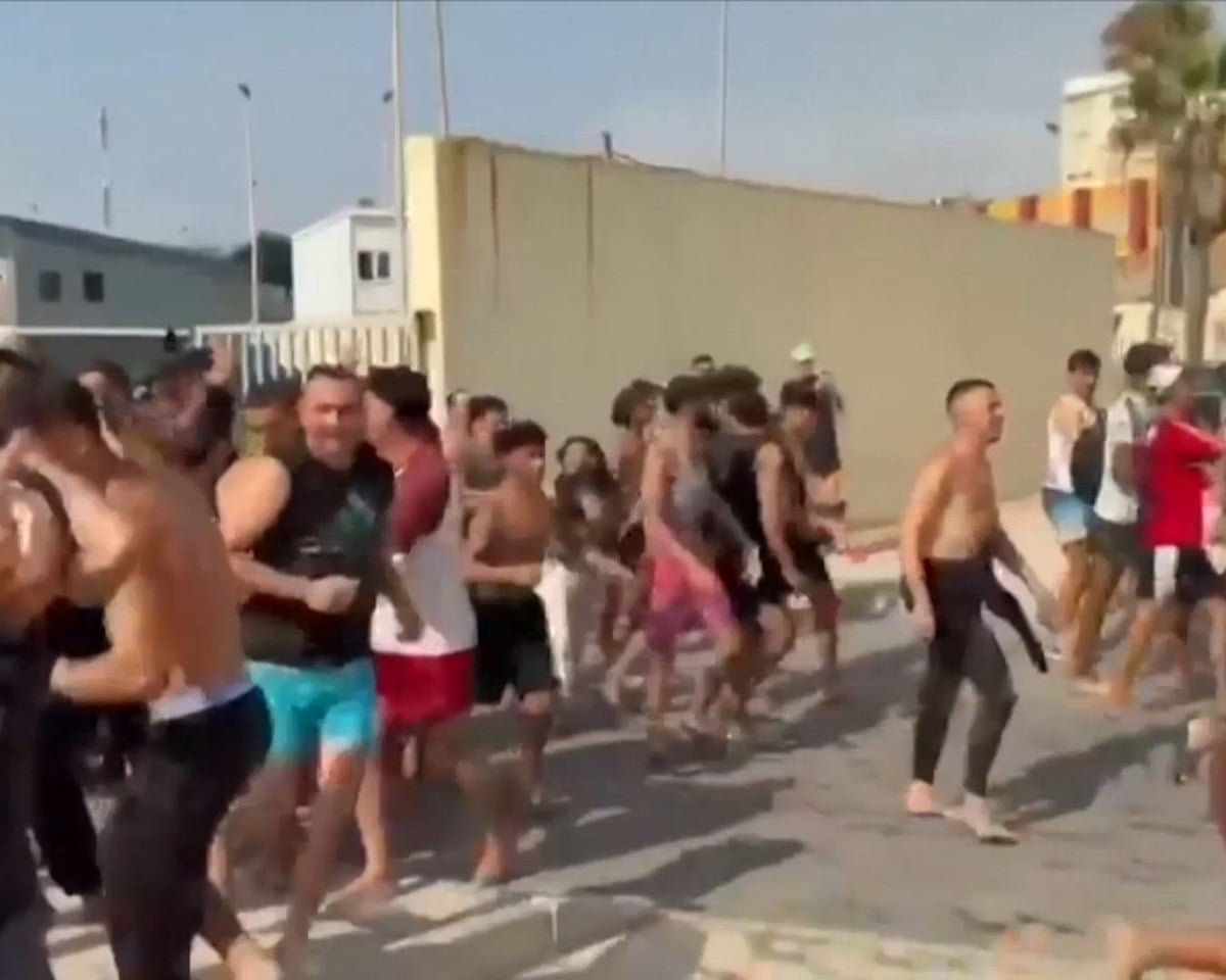 Hundreds of migrants run and cheer as they enter Spain’s enclave of Ceuta