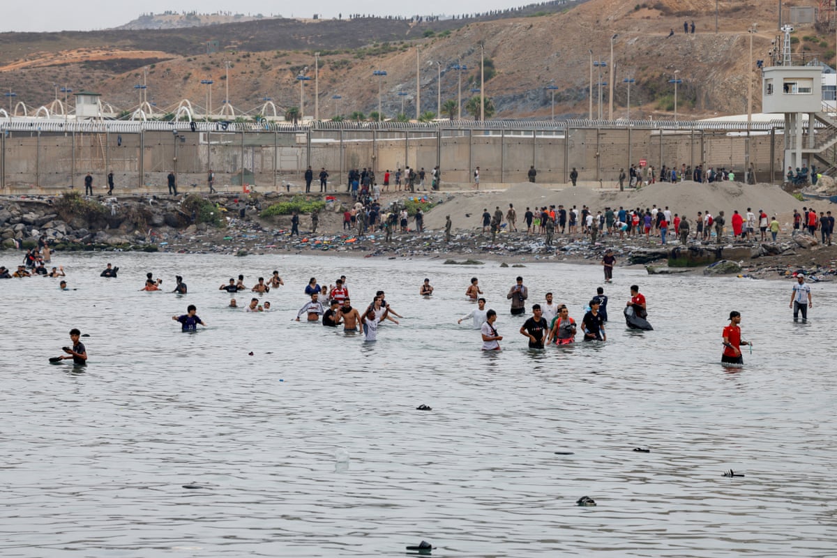 People wade through water to enter the Spanish territory of Ceuta.