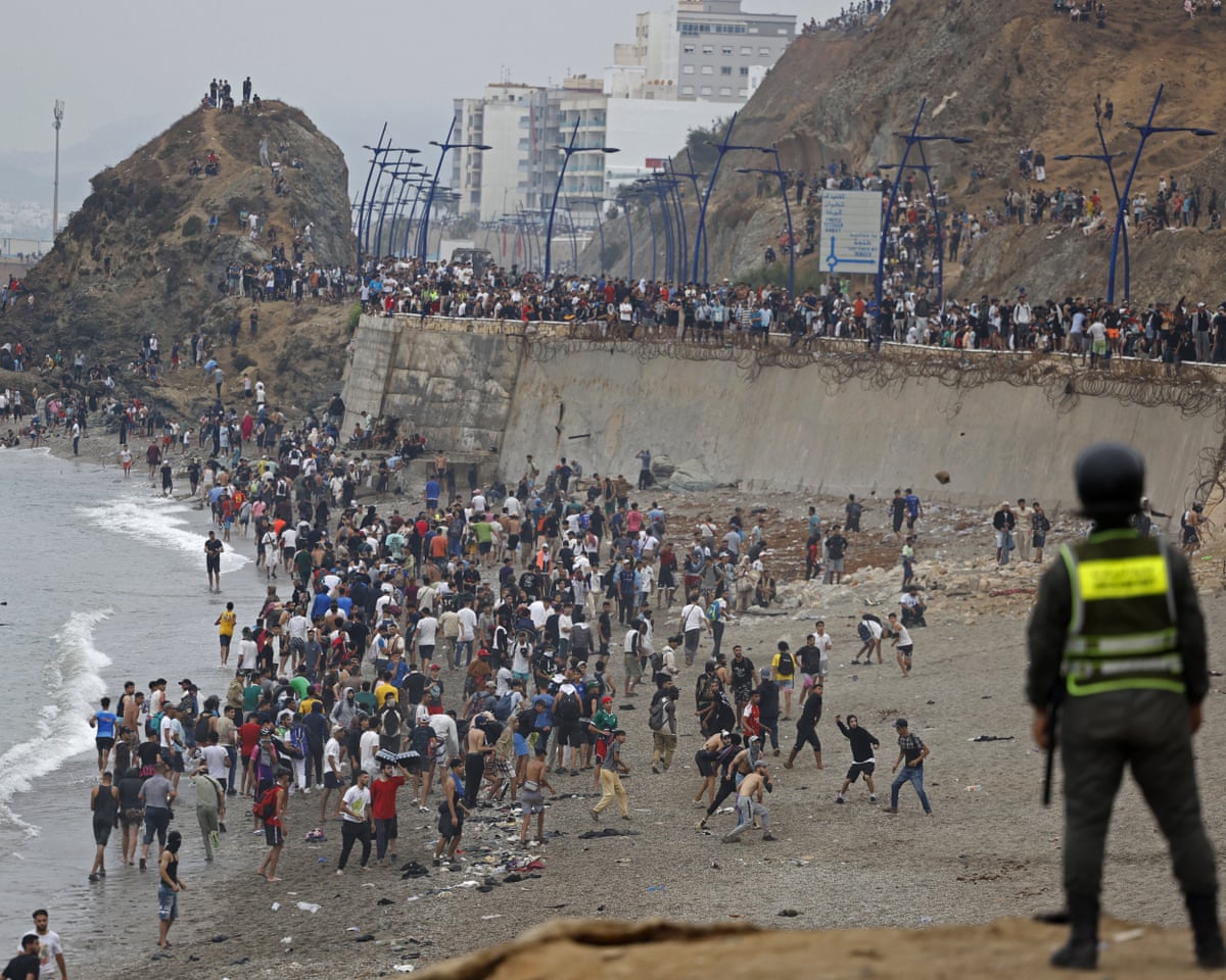People gather along the fence at the site of clashes near Fnideq, on the Morocco-Spain border.