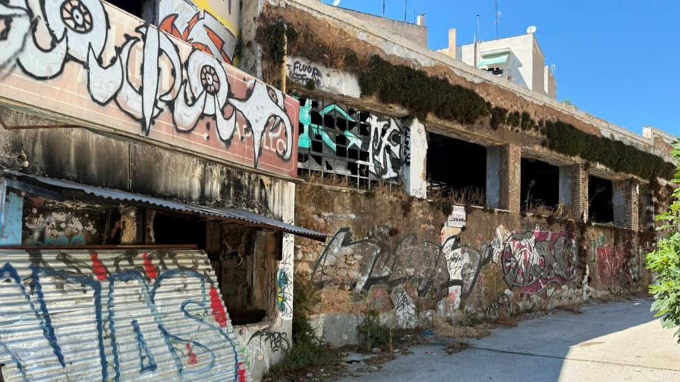 An abandoned building with missing windows is covered in graffiti