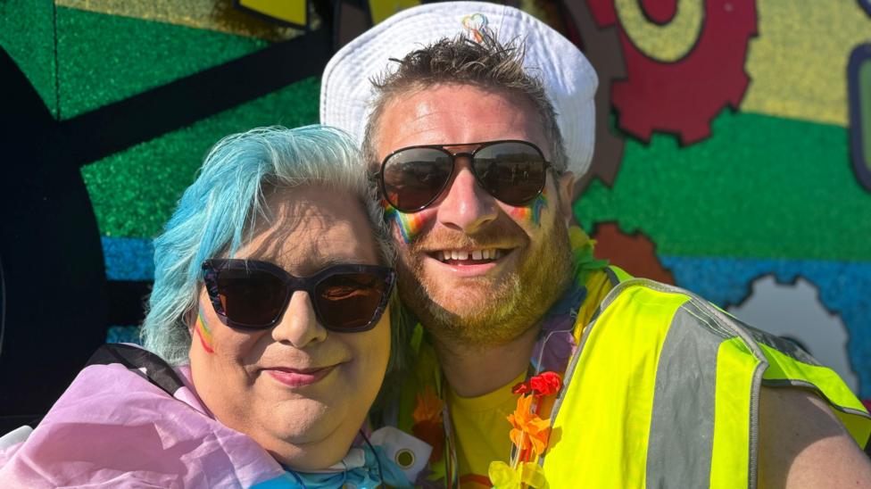 Two people in colourful rainbow clothing.