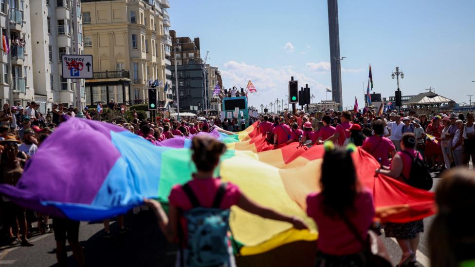 People carry a giant rainbow flag, as they take part in the Brighton & Hove Pride Community Parade during the annual Brighton Pride Festival in Brighton