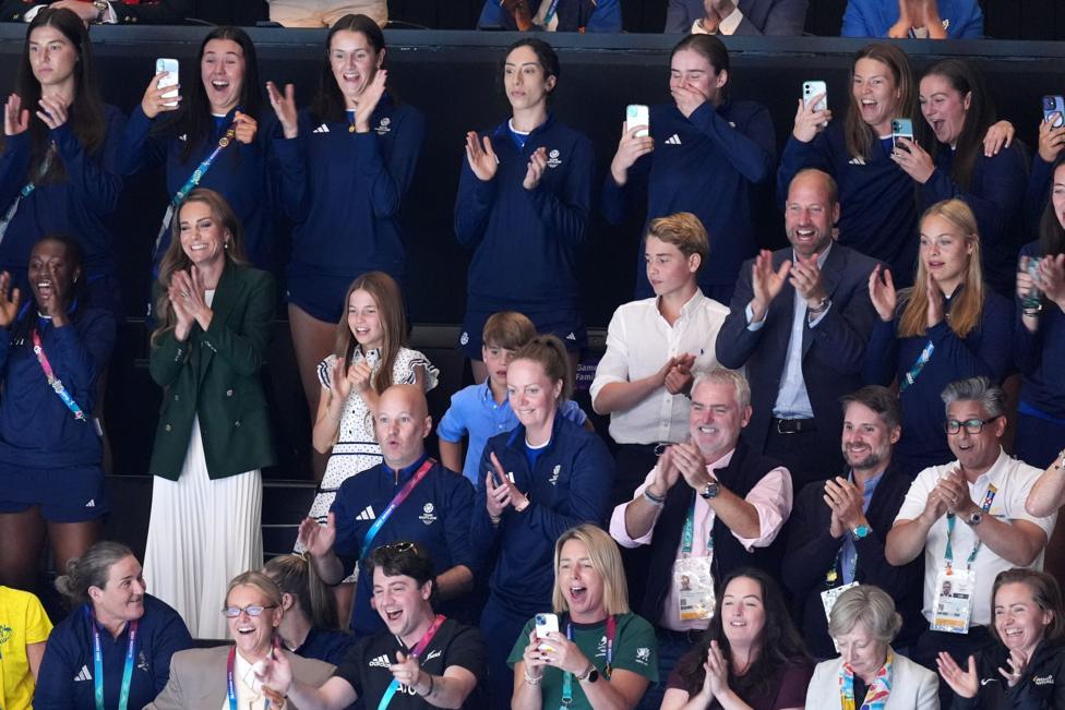 The royal family stand and applaud along with the rest of a crowd at a netball match