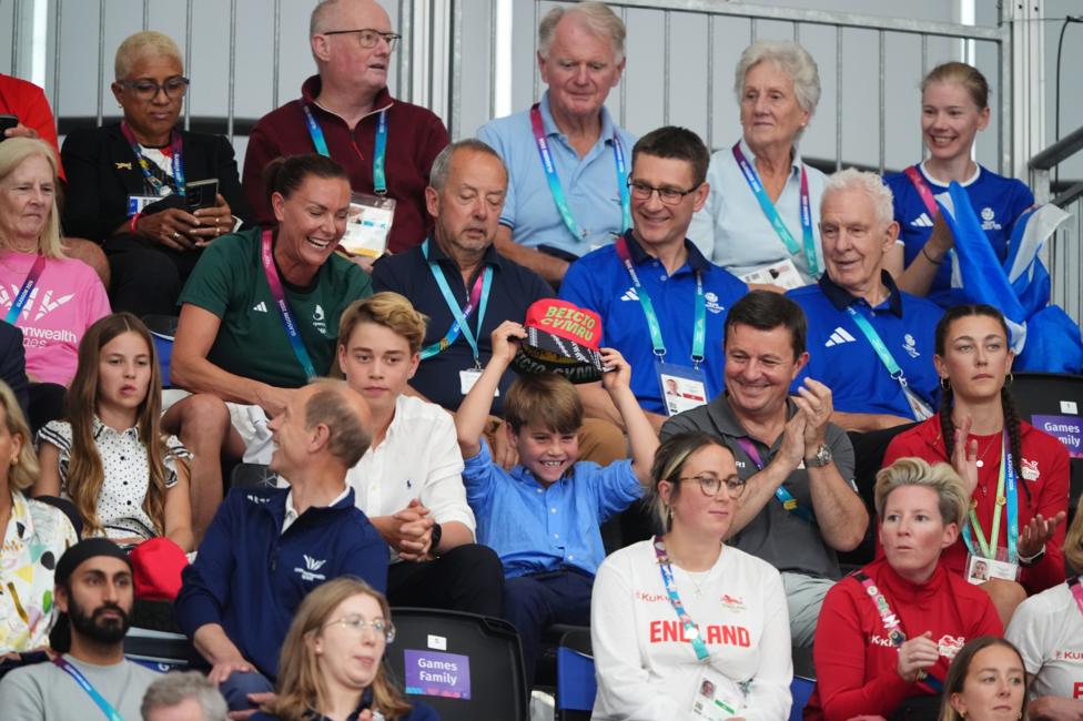 A crowd at the Sir Chris Hoy Velodrome , including the three royal children Charlotte, George and Louis. Louis is laughing and holding a hat above his head