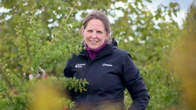 A woman stood in some bushes.