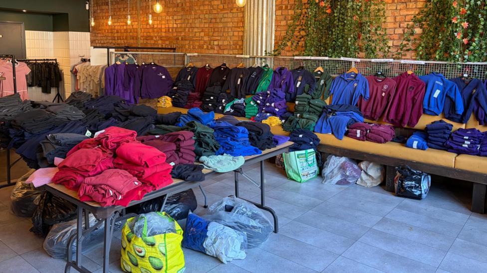 The inside of the pop-up, where tables in the middle of the space have folded clothes in different colours on them.