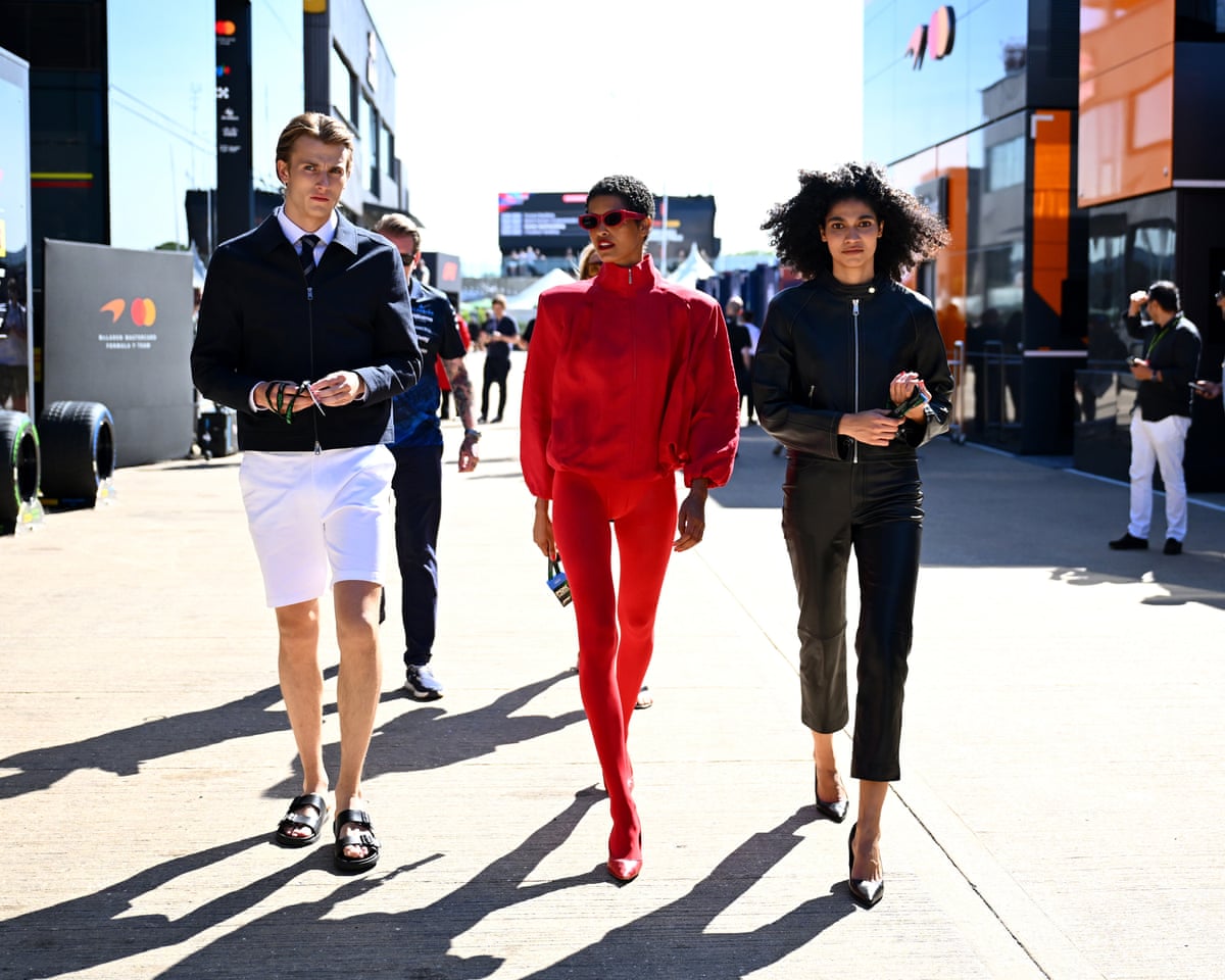 Three models walk through a paddock area at a Grand Prix event in M&S clothes outfits