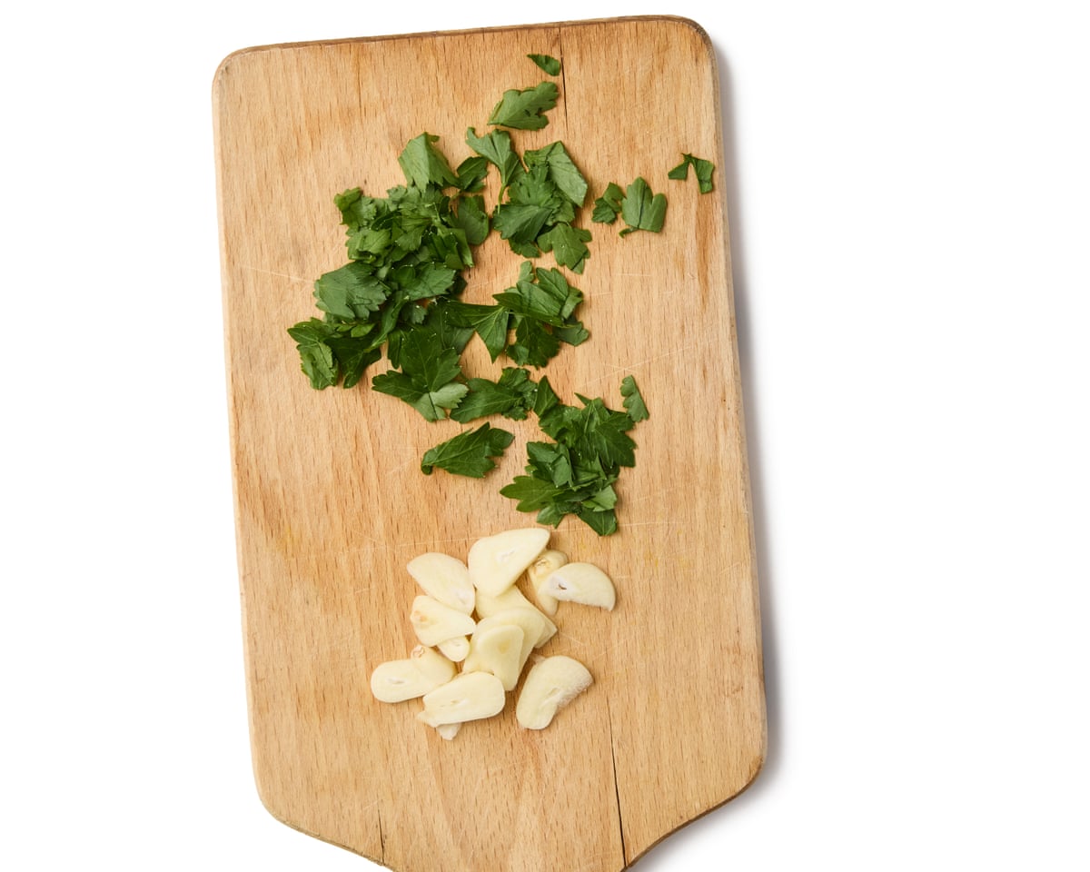 A chopping board with chopped parsley and garlic