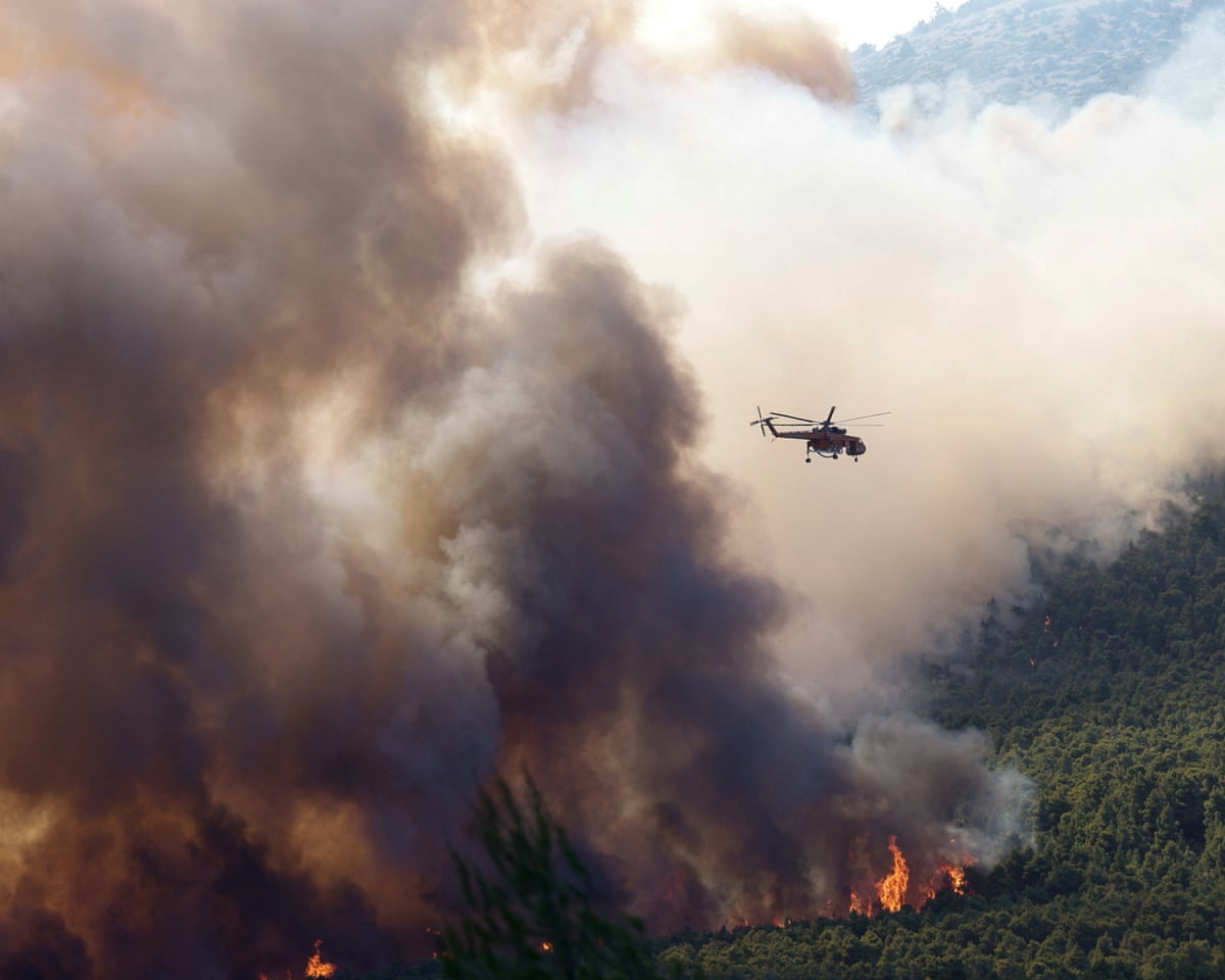 A firefighting helicopter flies over a wildfire