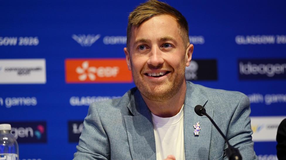 Phil Batty smiling. He is in a blue jacket and white T-shirt and has blonde hair.
